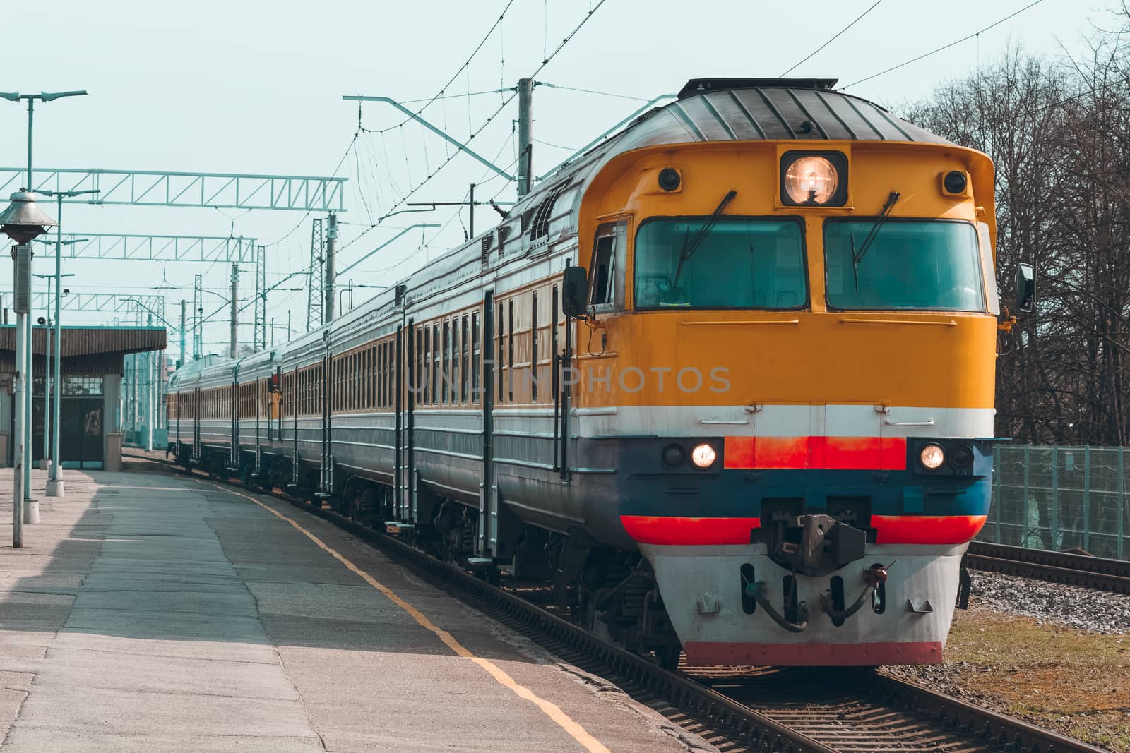 Old yellow passenger diesel train moving at the terminal