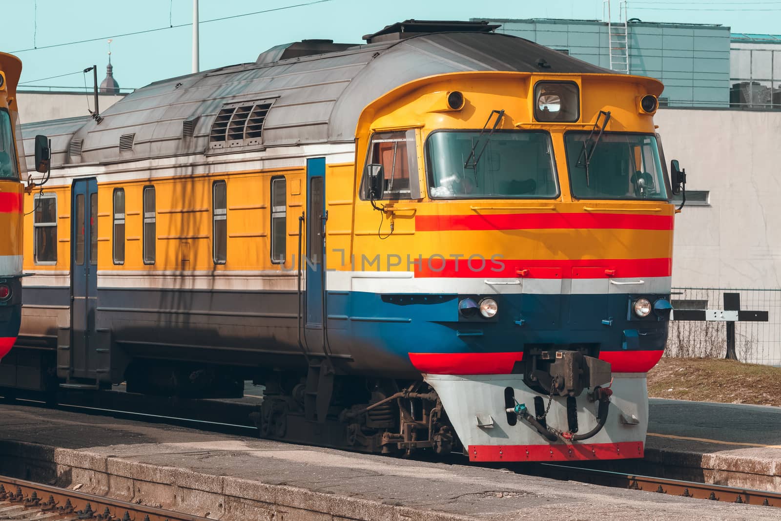 Old yellow passenger diesel train moving at the terminal