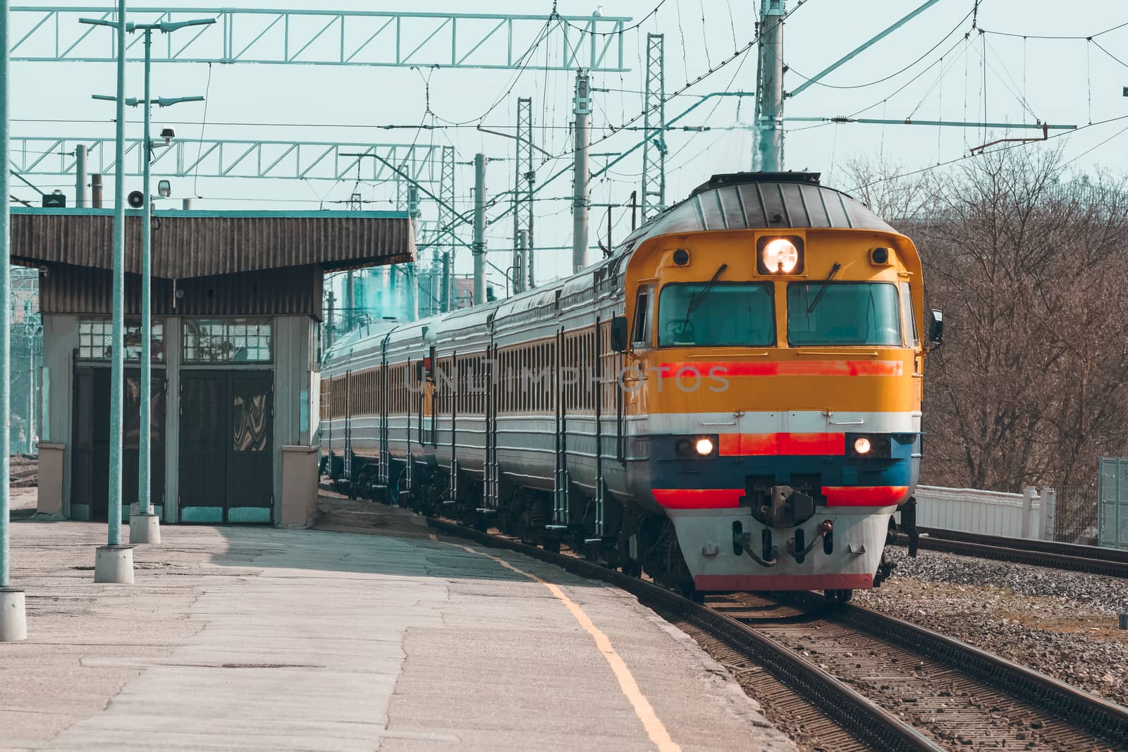 Old yellow passenger diesel train moving at the terminal