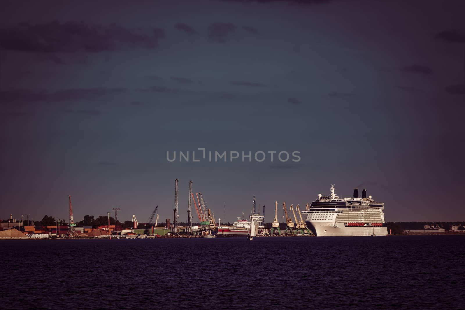 Giant white passenger ship moving past the port on a clear day