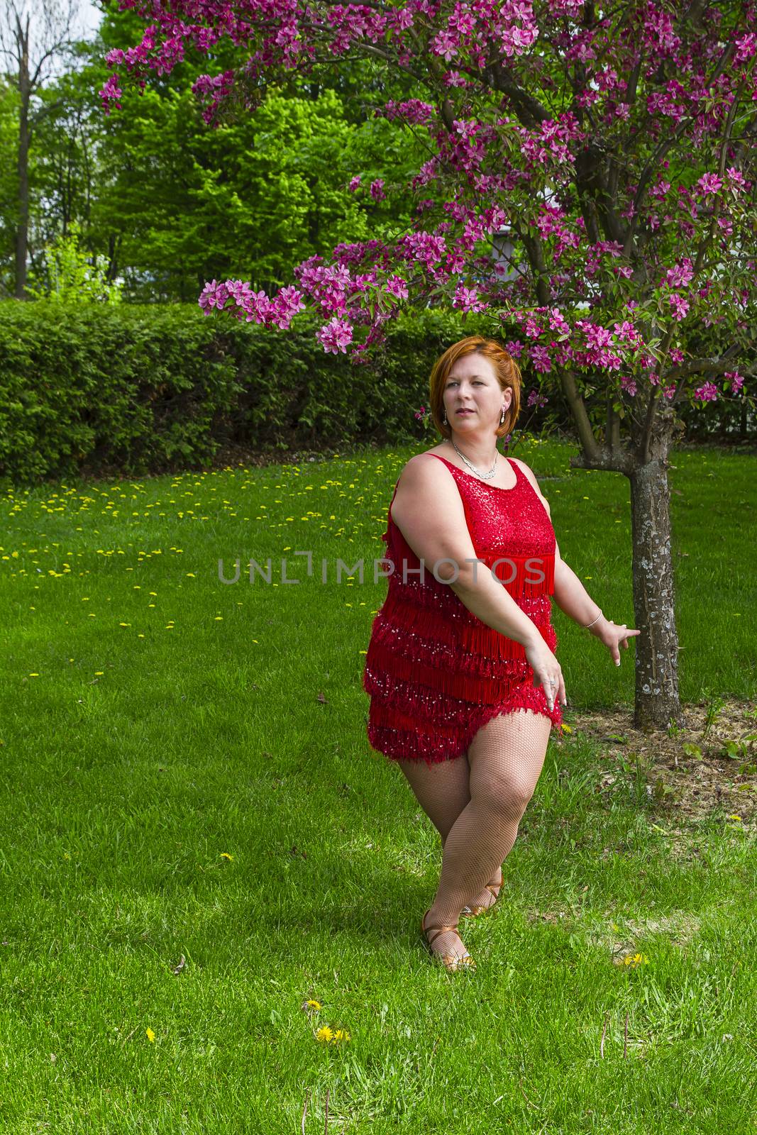 woman wearing a red dress dancing under a cherry tree in bloom