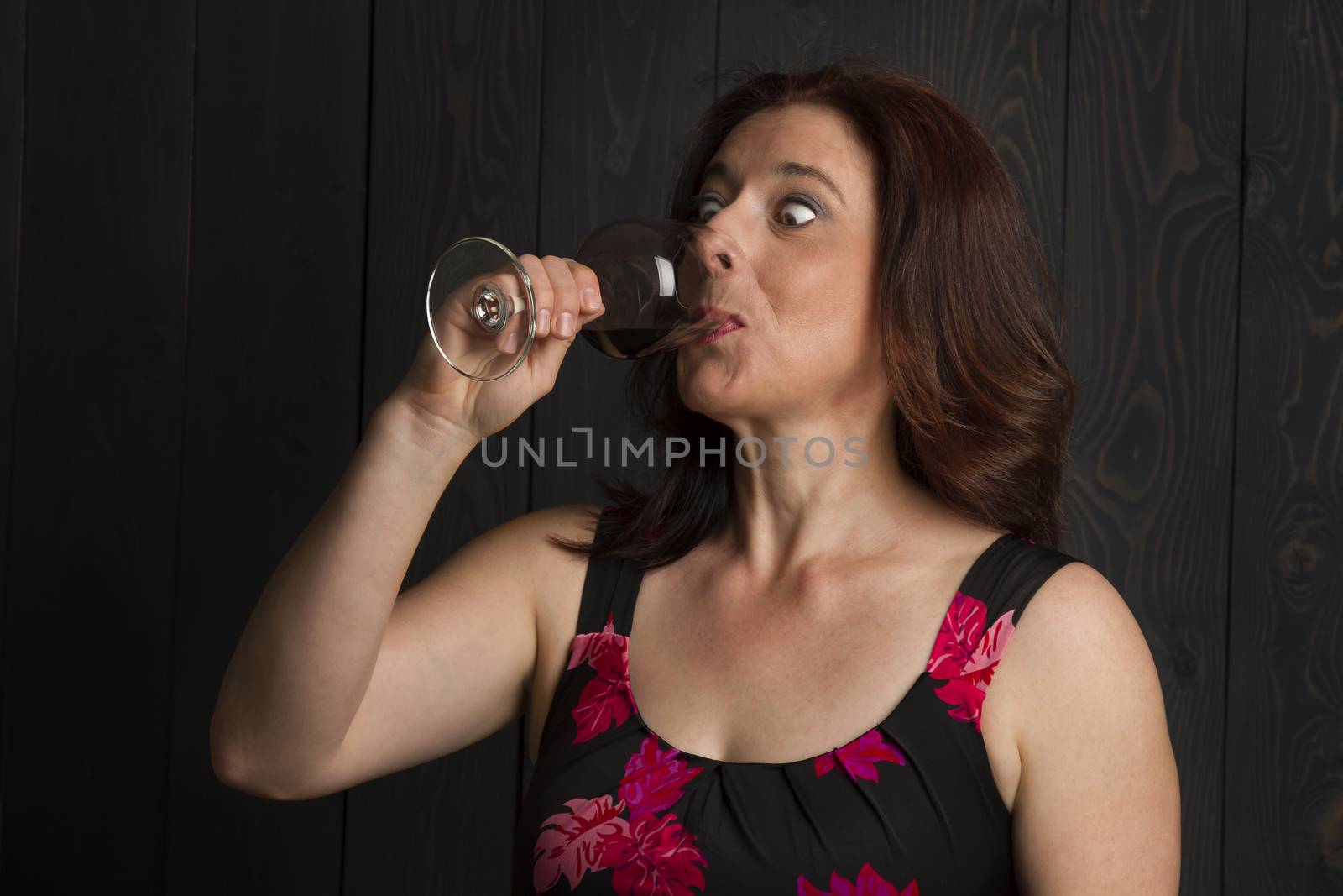 woman in her forties taking a big gulp out of a wine glass