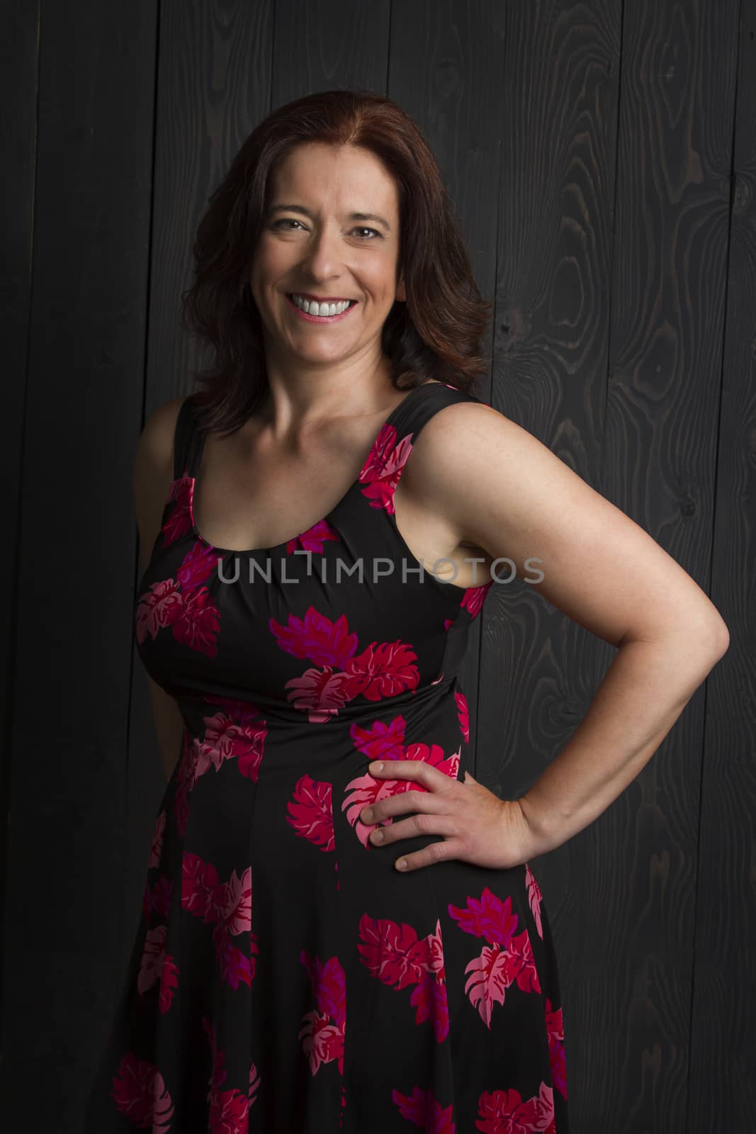 forty year old woman wearing a summer dress against a wood panel background