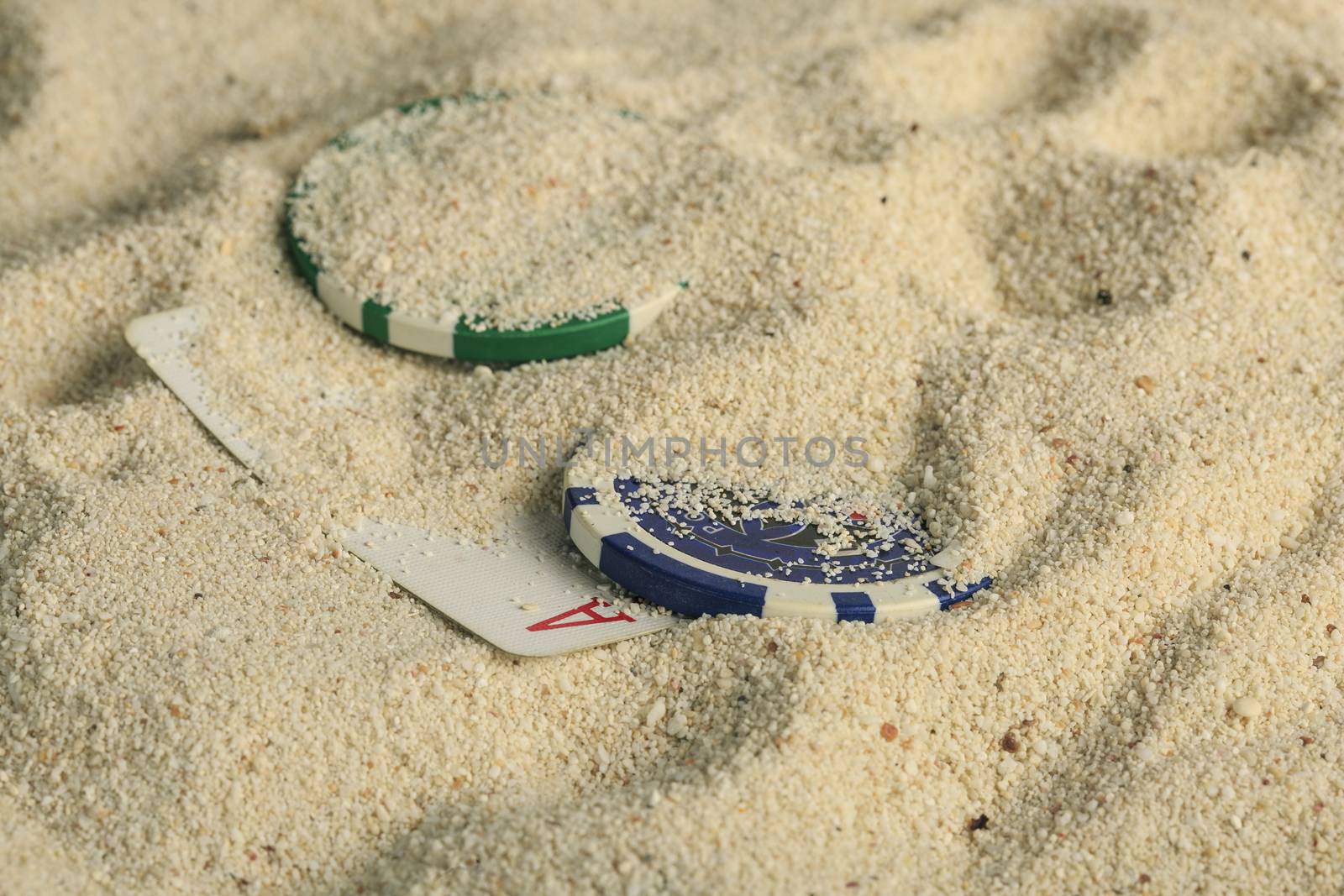 Poker playing cards and chips  buried  in a sand dune