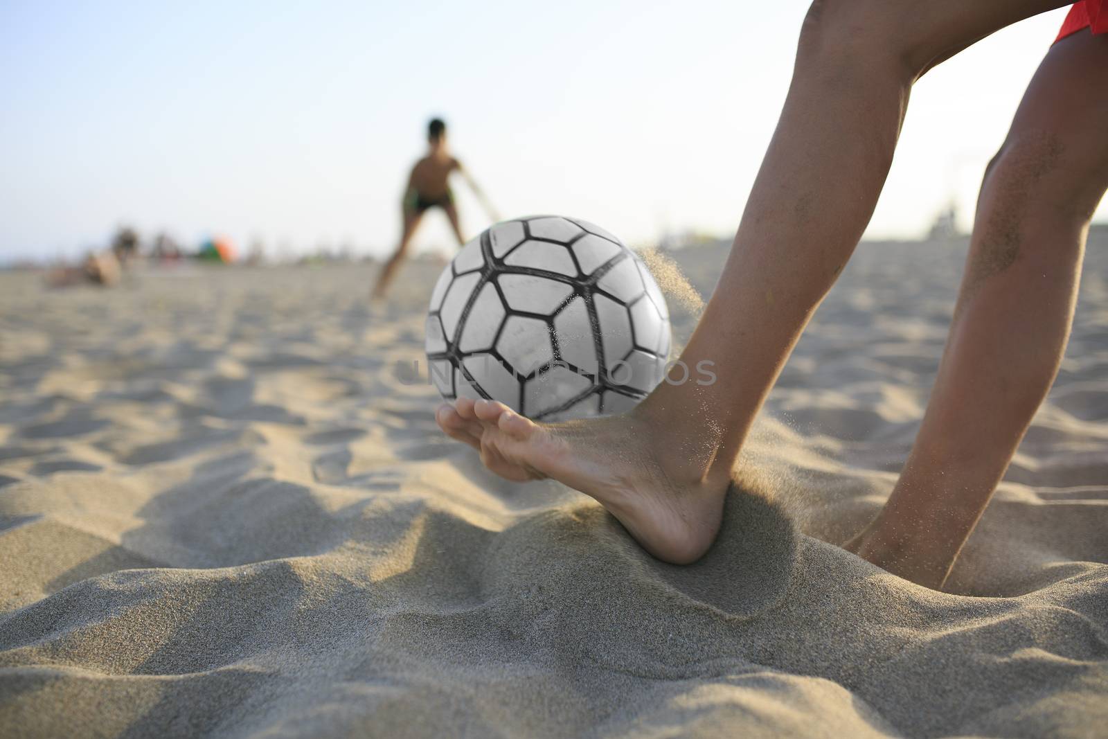 Boy playing football  on the beach