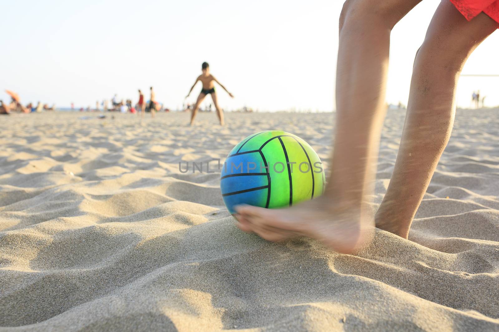 Boy playing football  on the beach