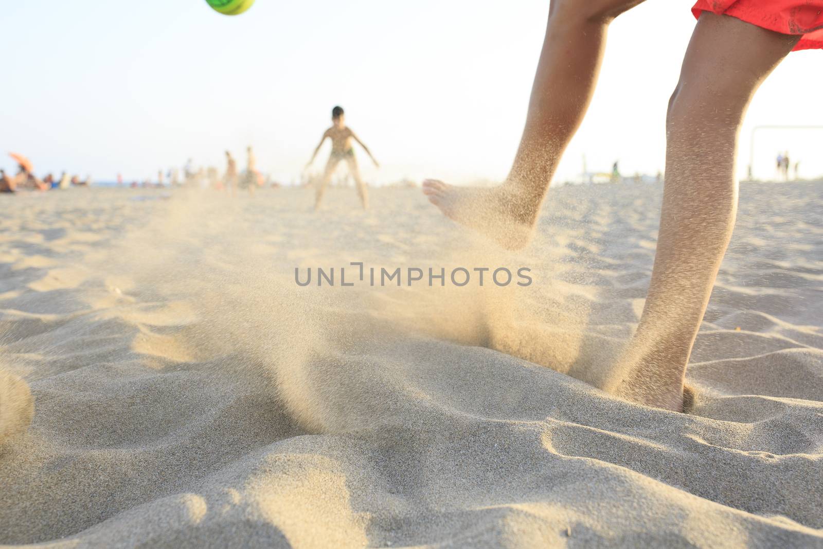 Boy playing football  on the beach