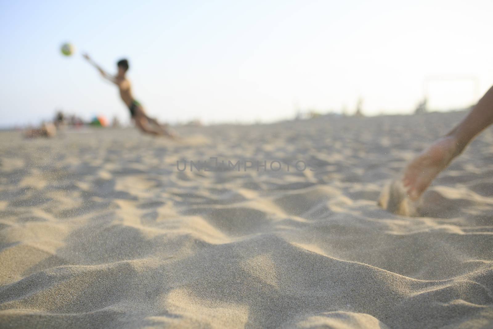 Boy playing football  on the beach