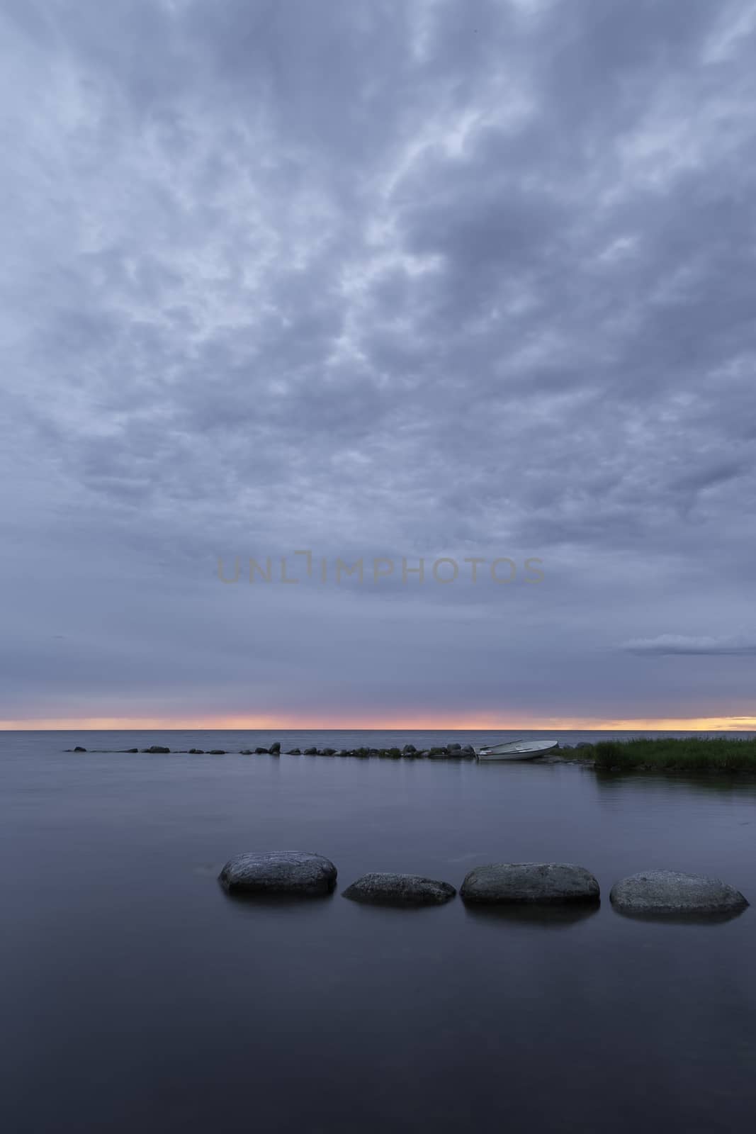 Rowboat by Ocean at Sunset with a partly cloudy sky.
