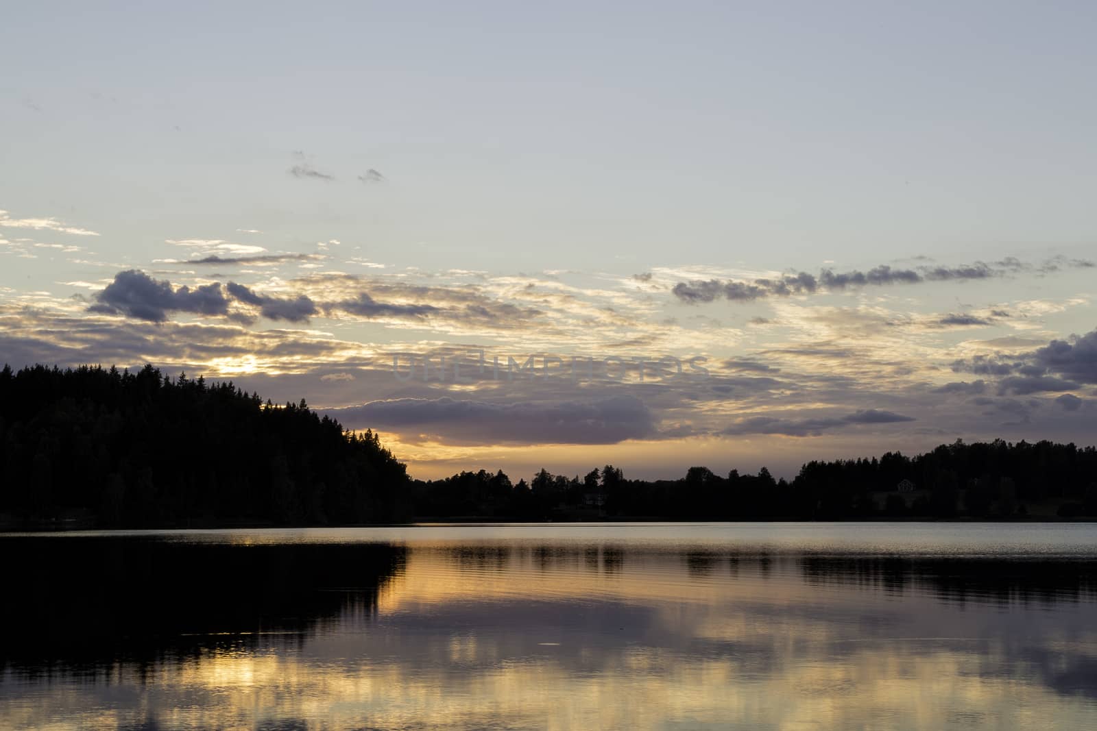 Sunset over Lake with Forest and clouds.