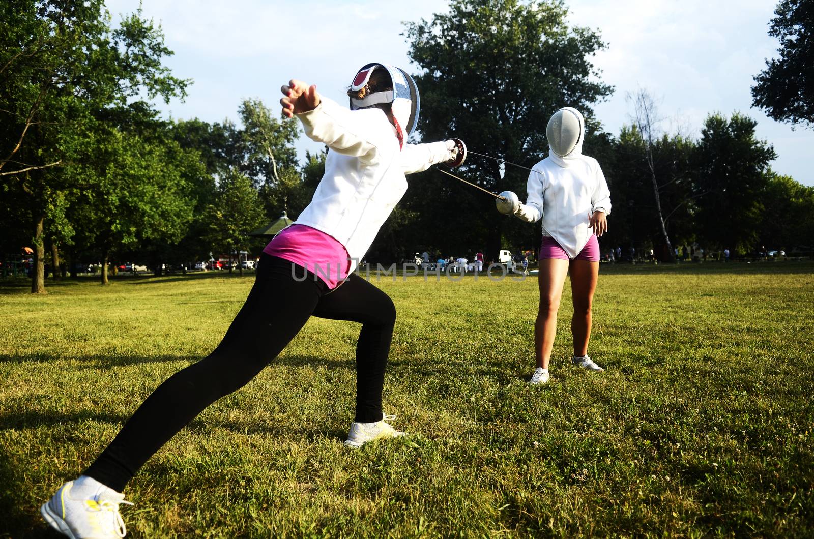 Two girls performing fencing in the park
