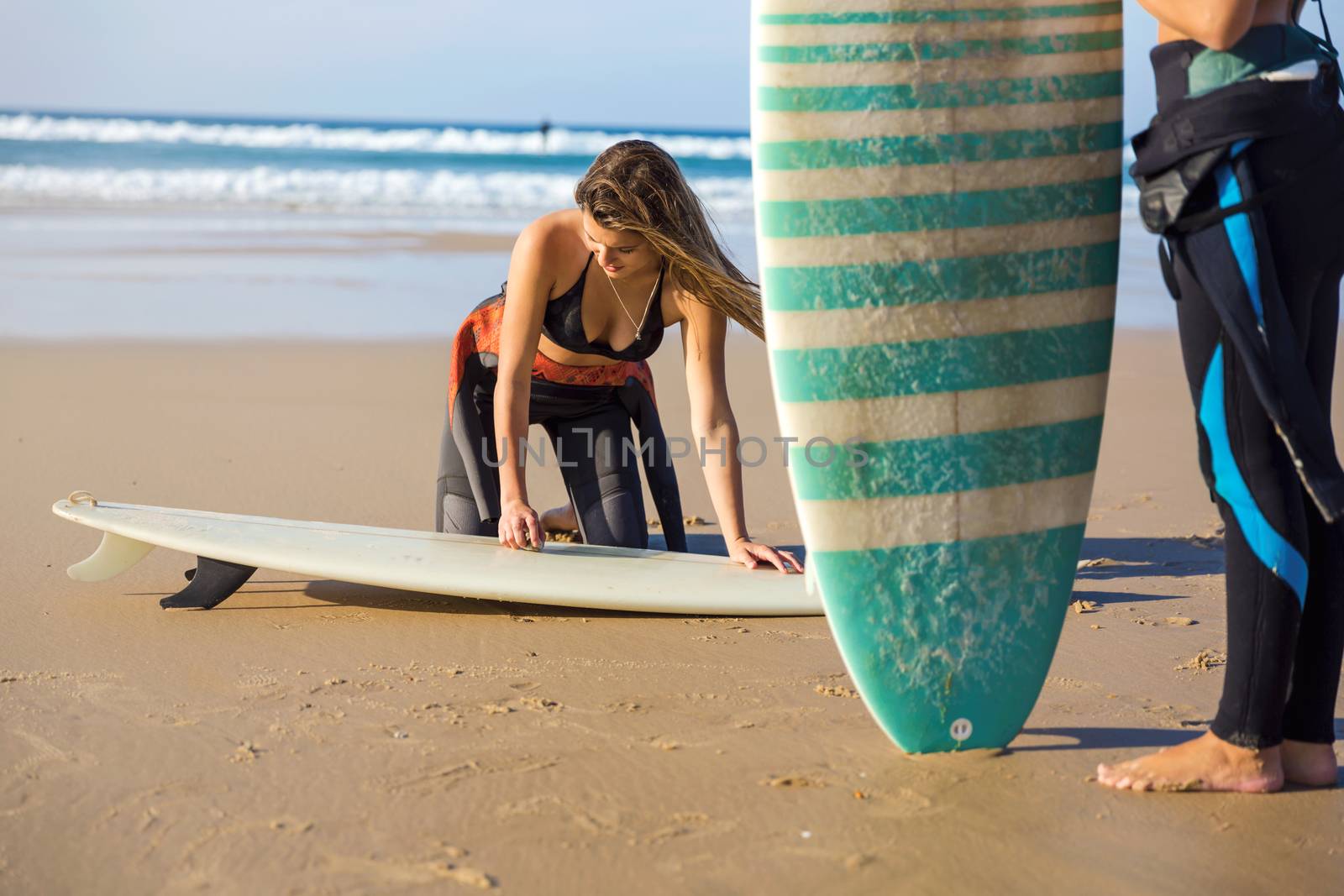 Two beautiful surfer girls at the beach getting ready for surfing