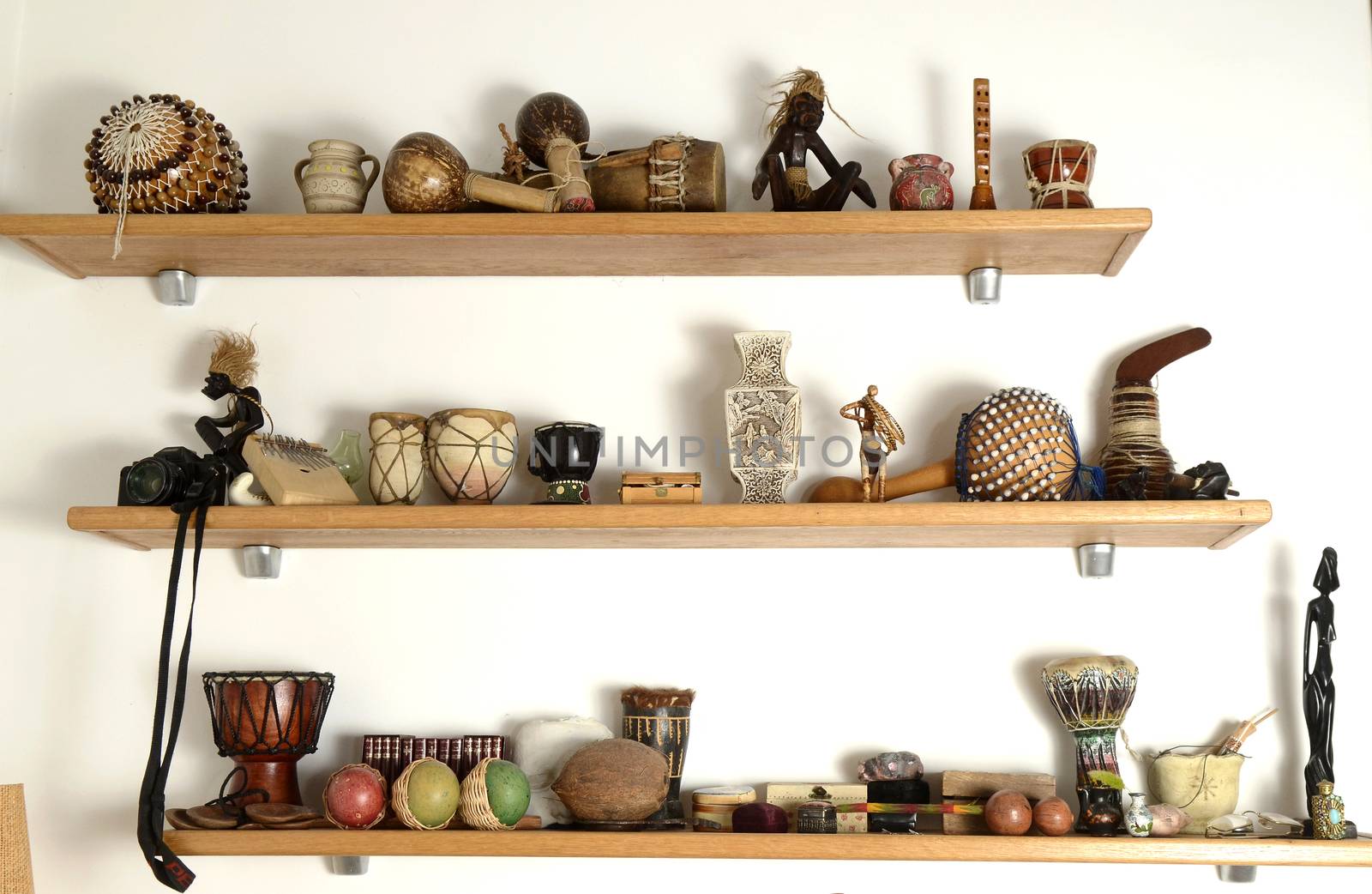 Many figurines on wooden shelf on the white wall