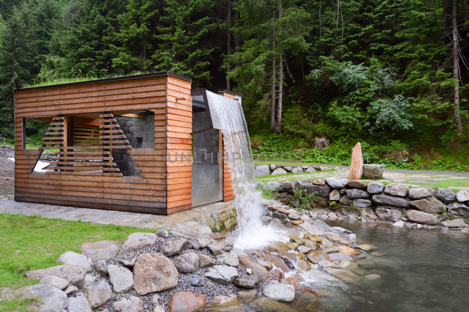 Artificial waterfall on a small wooden hut in a natural park in the dolomites in Italy