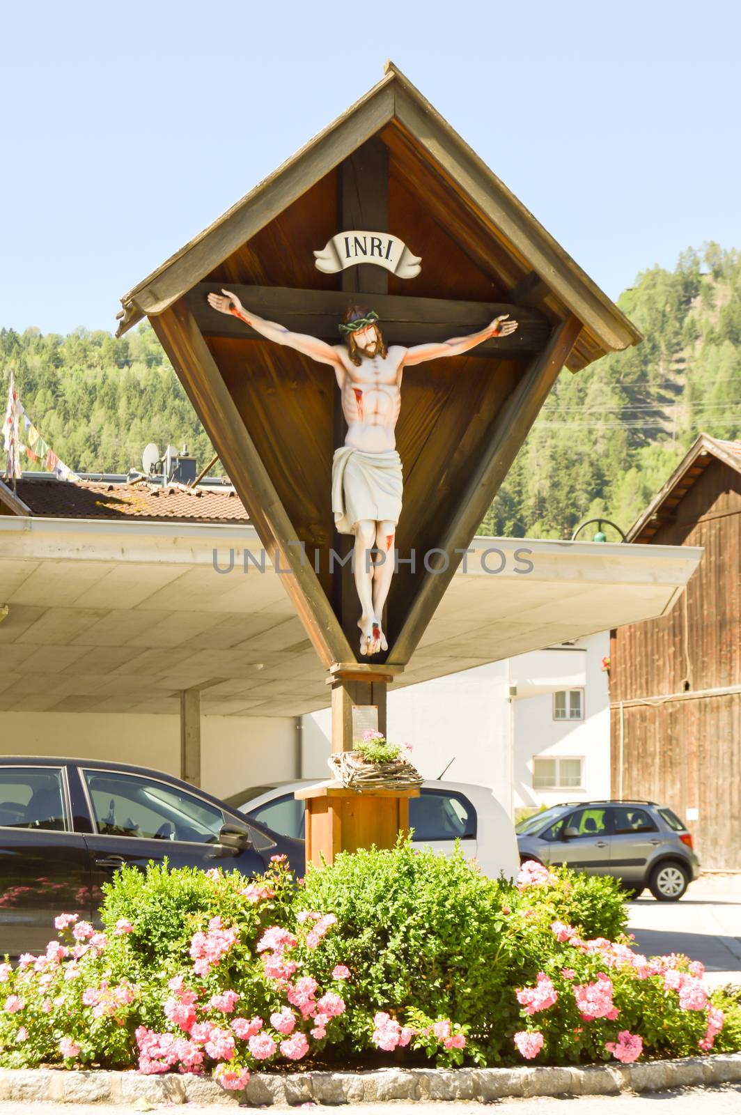 Crucifix over a flowerbed along a road in a valley of the Tyrol in Austria