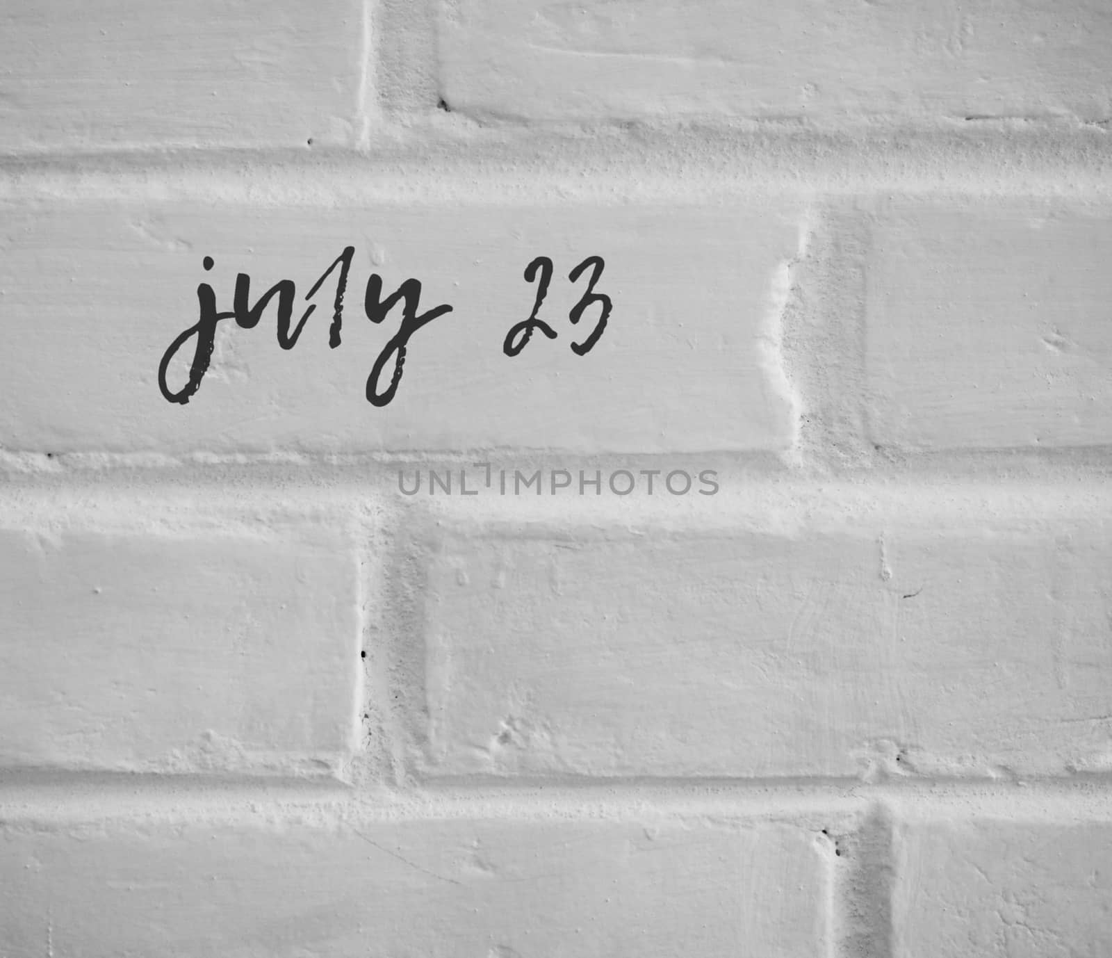 PHOTO OF july 23 WRITTEN ON WHITE PLAIN BRICK WALL