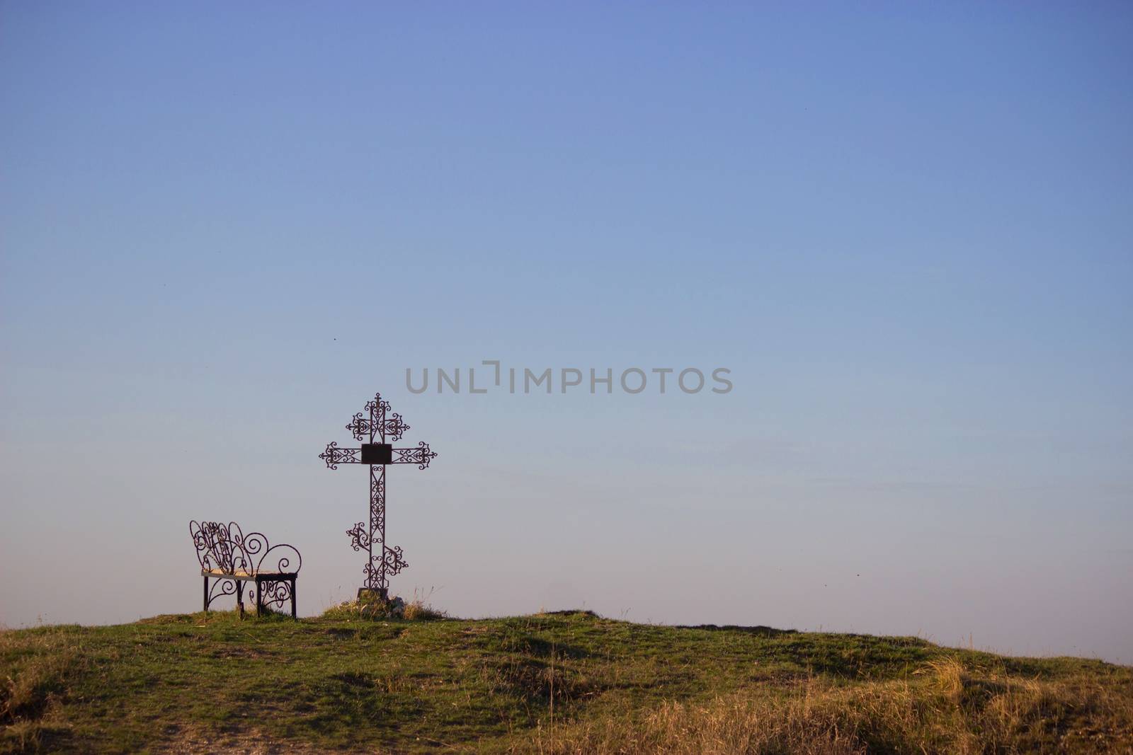 Graveyard cross and bench in silhouette. copy space