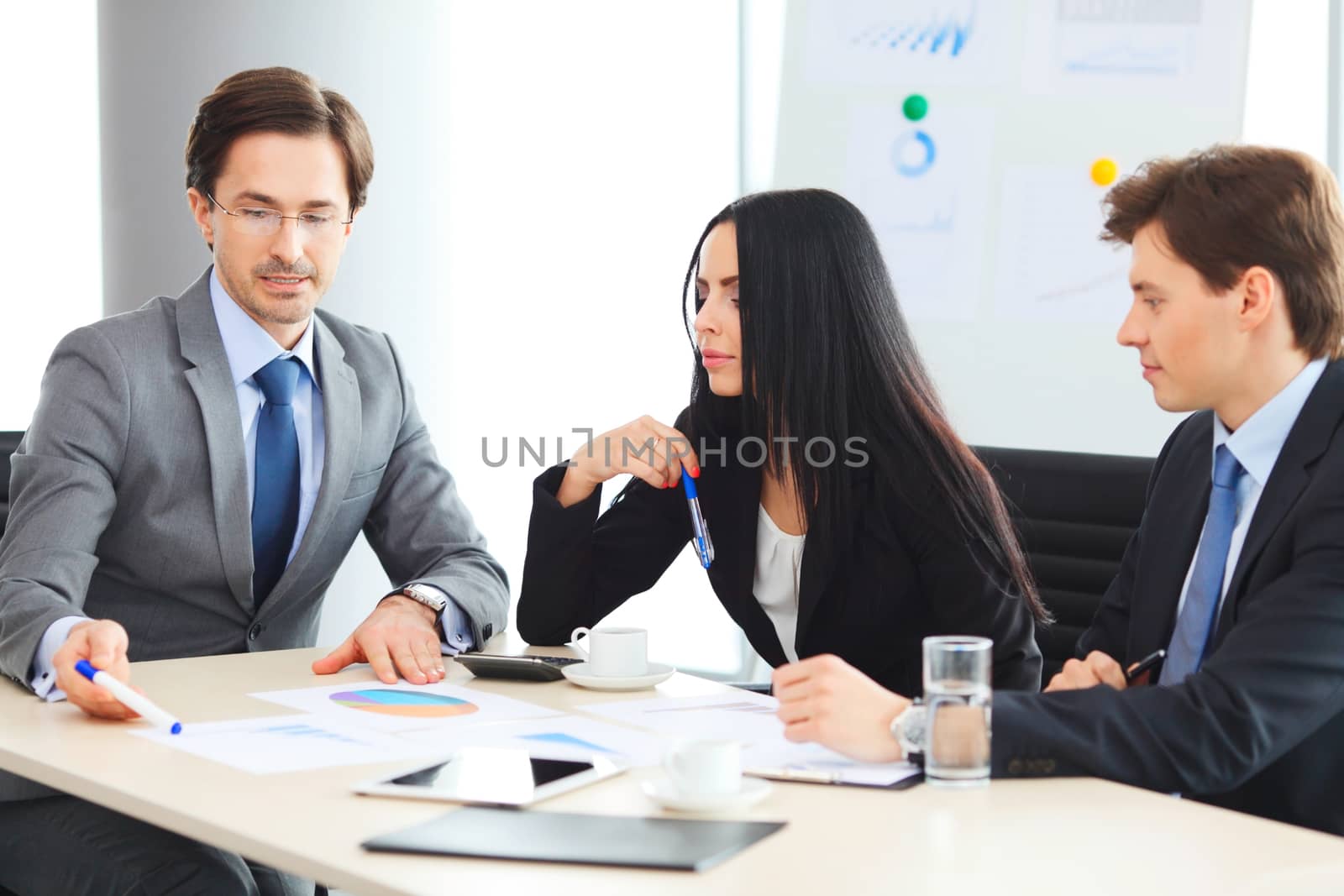 Workers at business meeting looking at presentation of financial reports in modern office