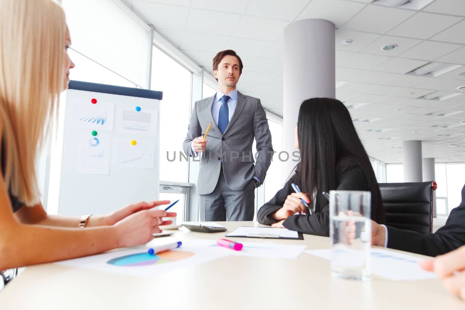 Workers at business meeting looking at presentation of financial reports in modern office