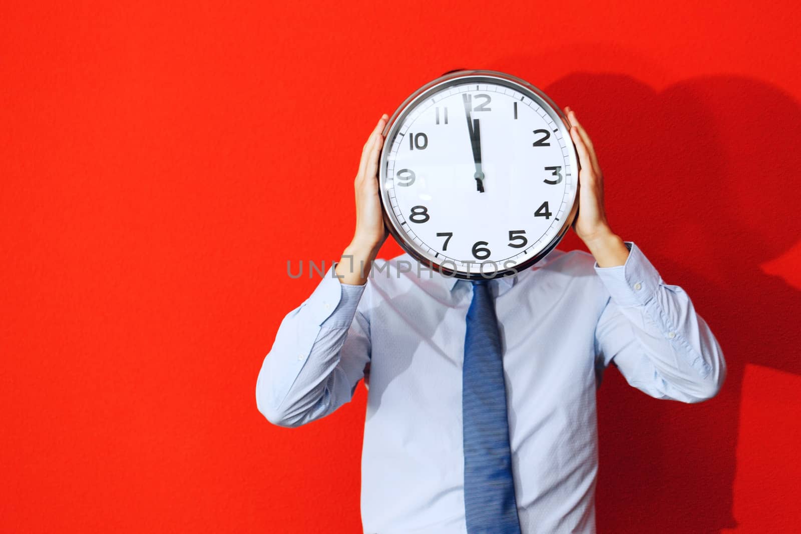 Man with wall clock on red background, deadline concept
