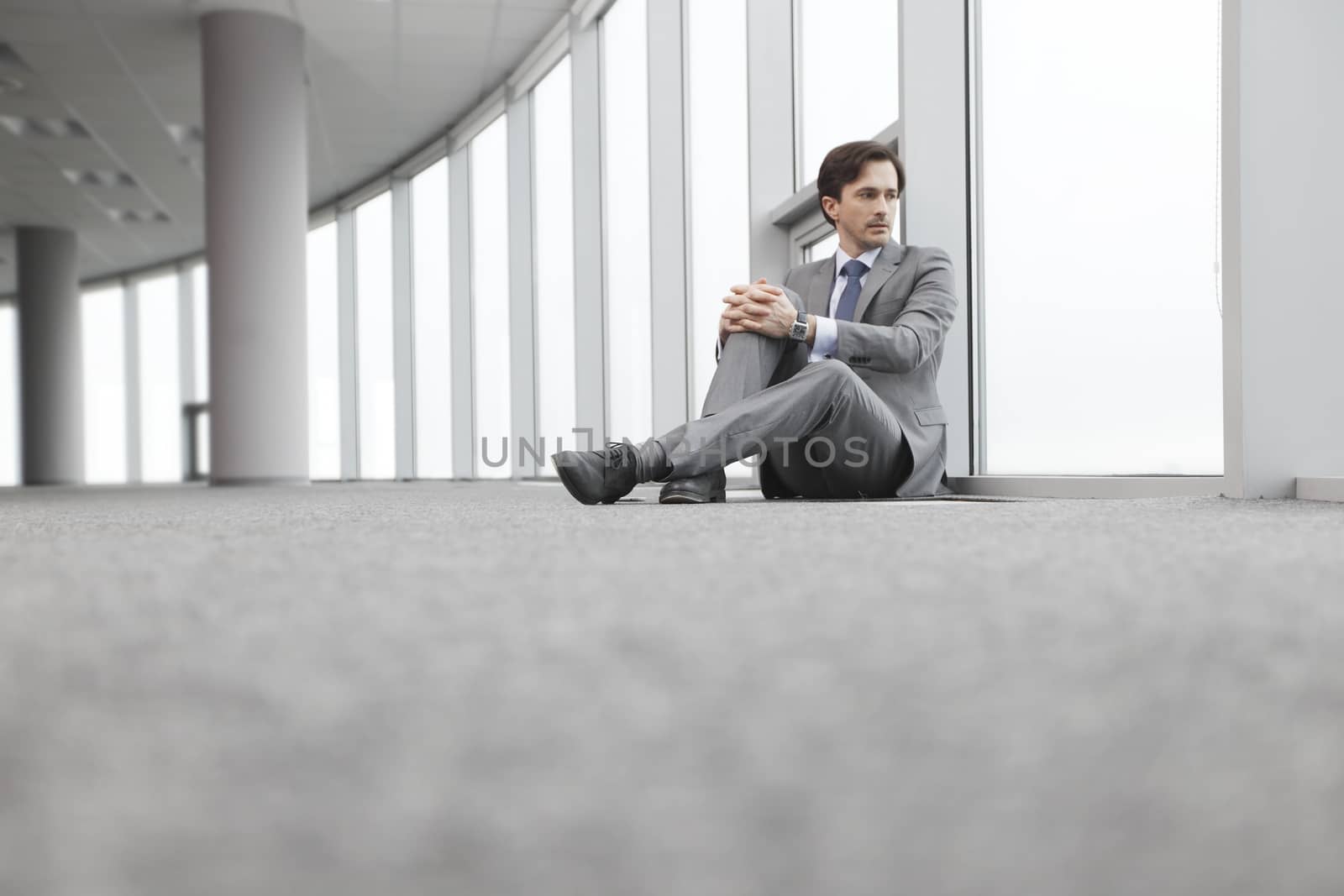 Businessman sitting on floor in office near window