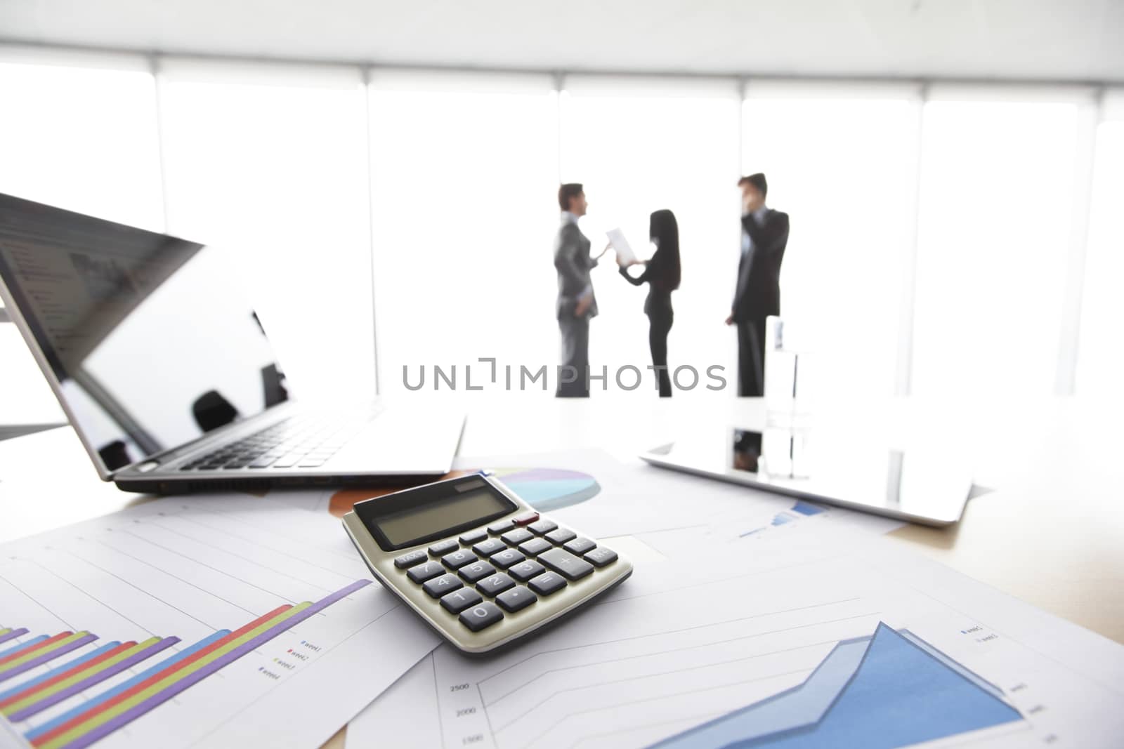 Financial reports, calculator and laptop on table in office