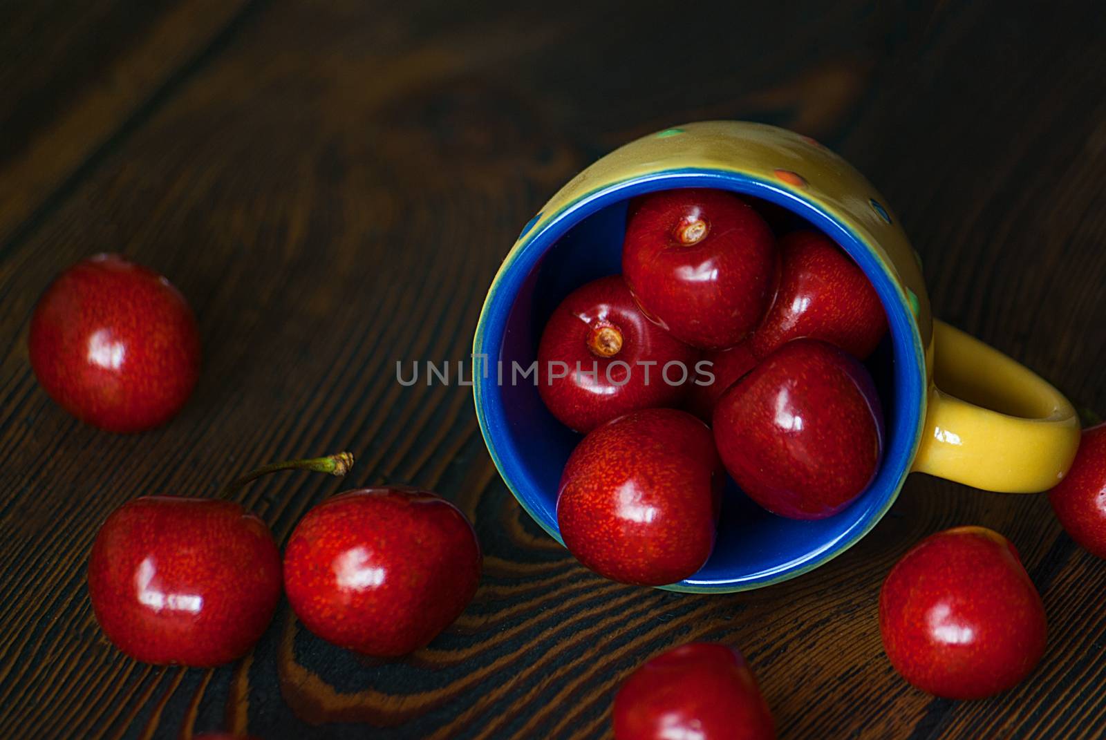 Fresh cherries in jar on the wooden background. Selective focus. Focus on the right cherries in front of jar.