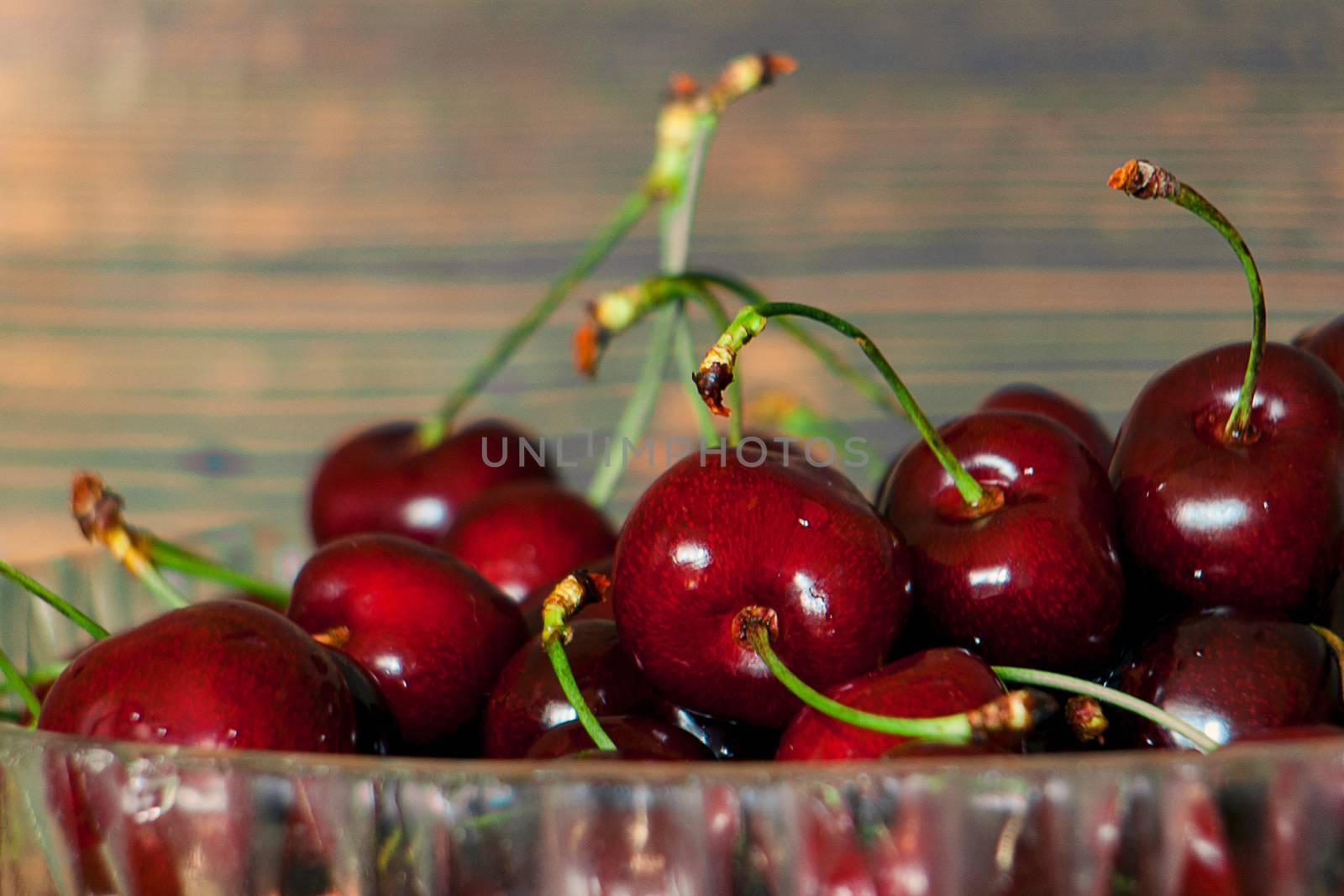 Fresh cherries in jar on the wooden background. Selective focus. Focus on the right cherries in front of jar.
