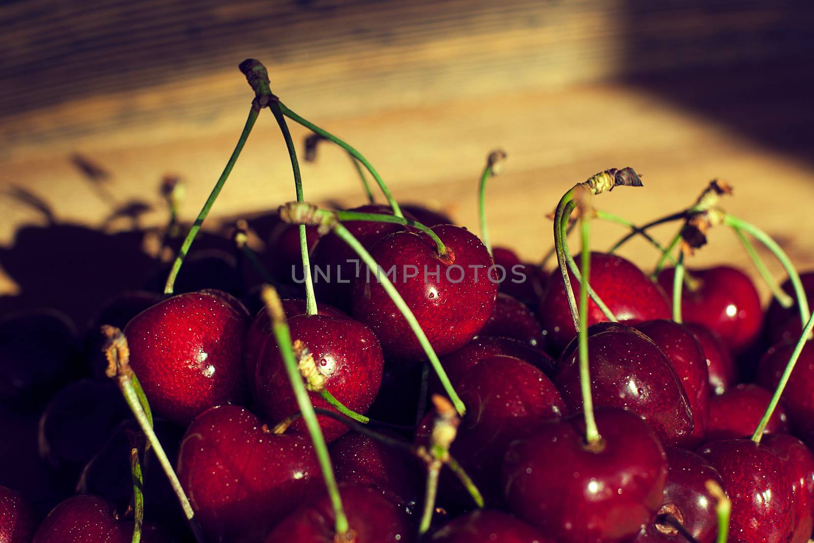 Fresh cherries in jar on the wooden background. Selective focus. Focus on the right cherries in front of jar.