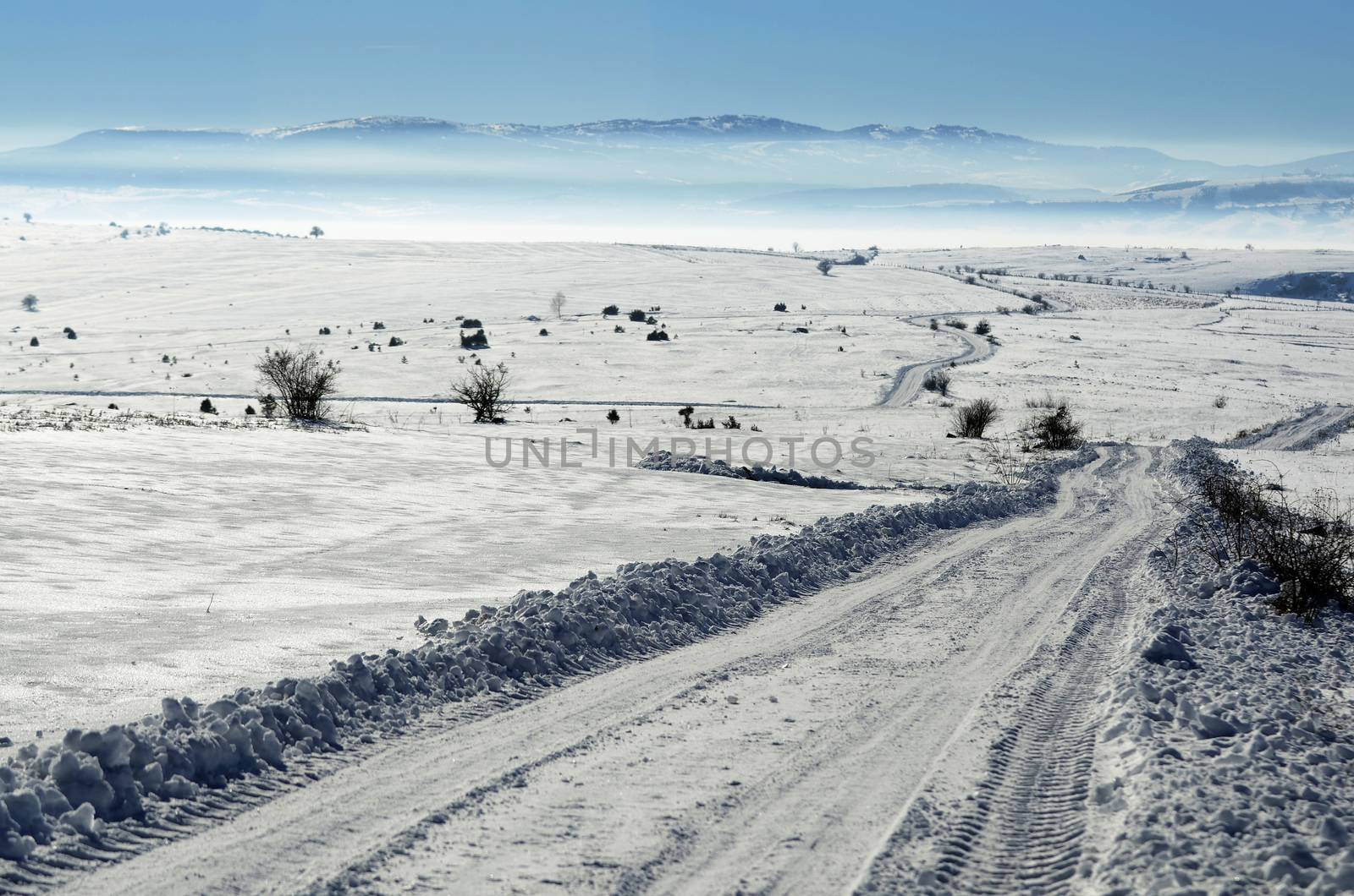 Landscape of road on the empty field covered with snow and ice on sunny day