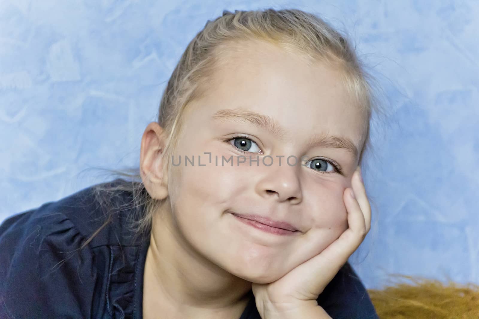 Cute smiling girl with blond hair on blue background