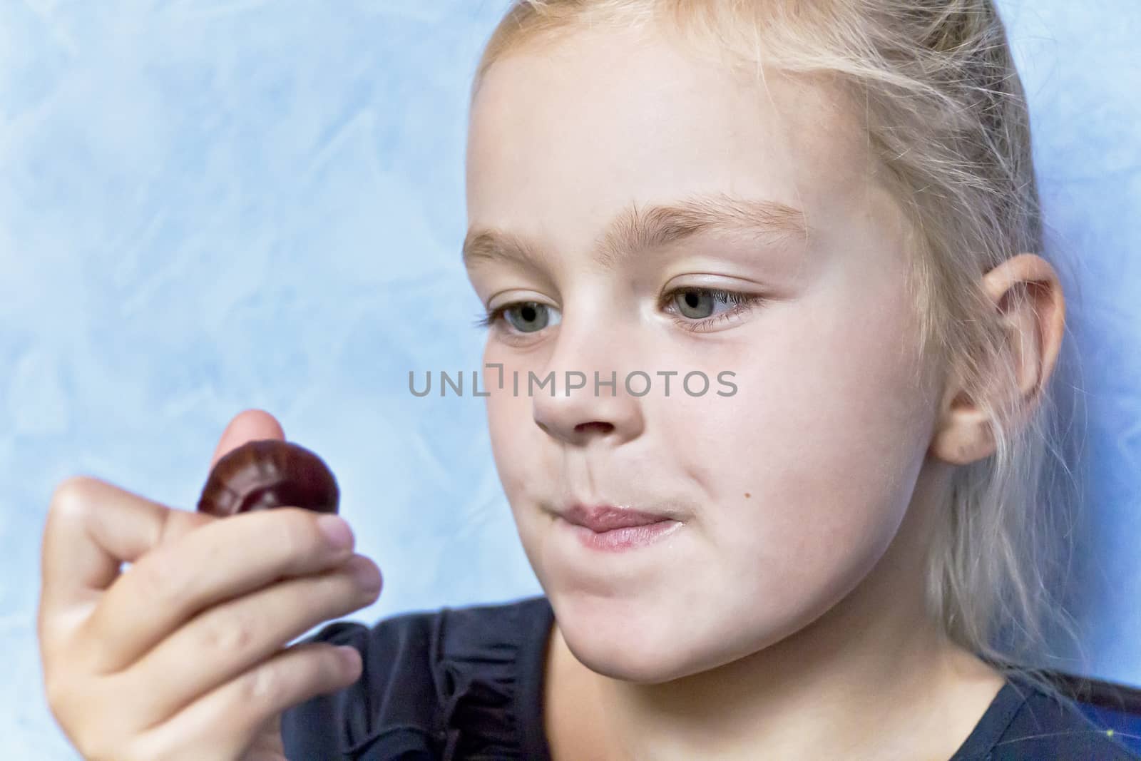 Cute eating girl with blond hair on blue background
