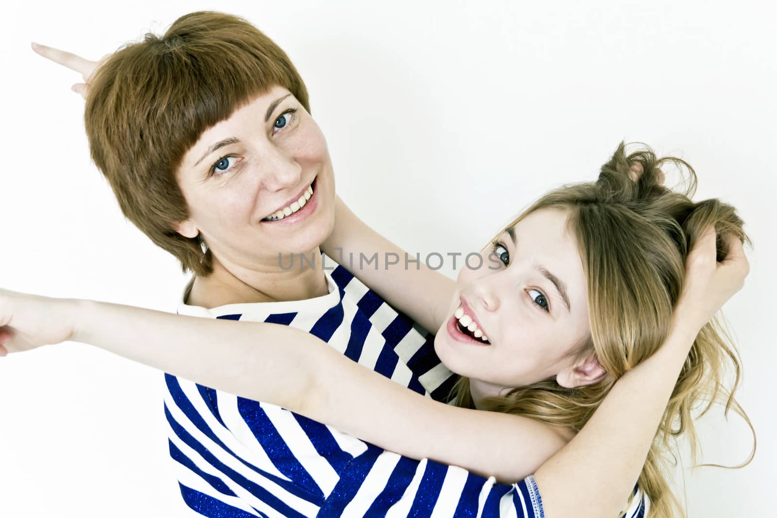 Happiest mother and daughter playing with blond long hair near white wall