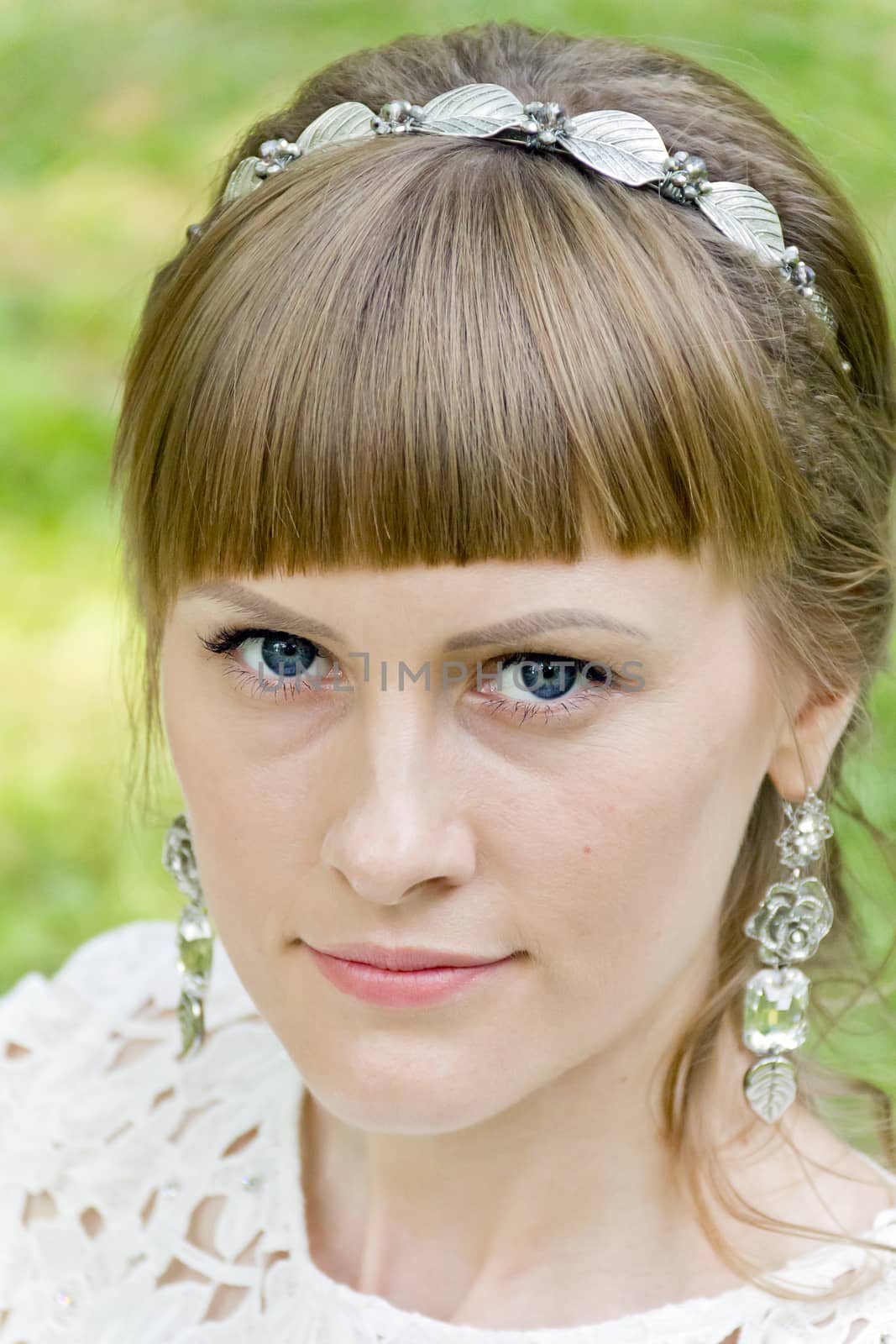 Portrait of blue eyes and blond hair bride with diadem on green background