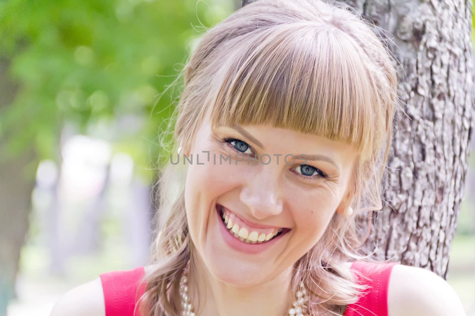 Portrait of smiling  blond girl with blue eyes on green wood background