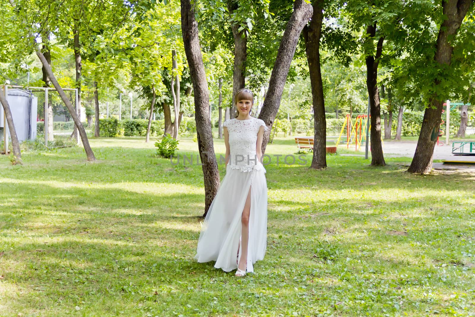 Bride in white lace dress walking in summer park
