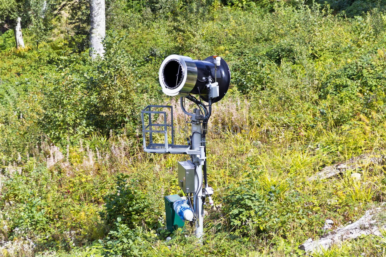 Snow cannon in summer time on green forest background