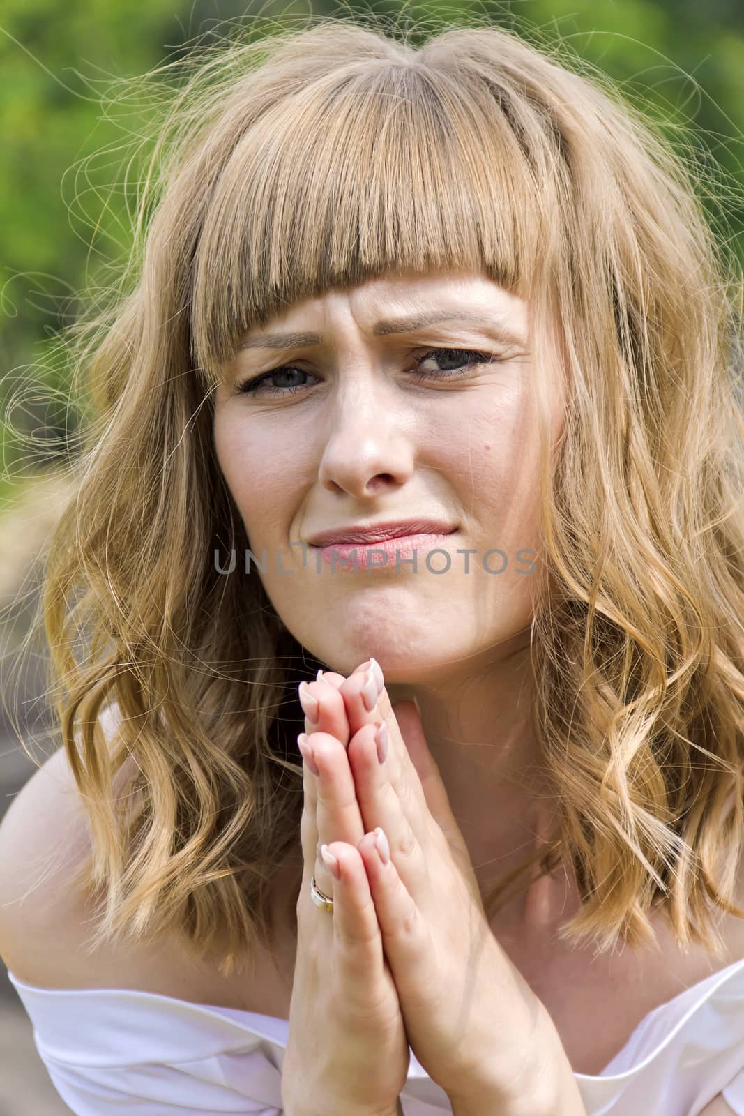 Young praying woman with blond hair in sunlight