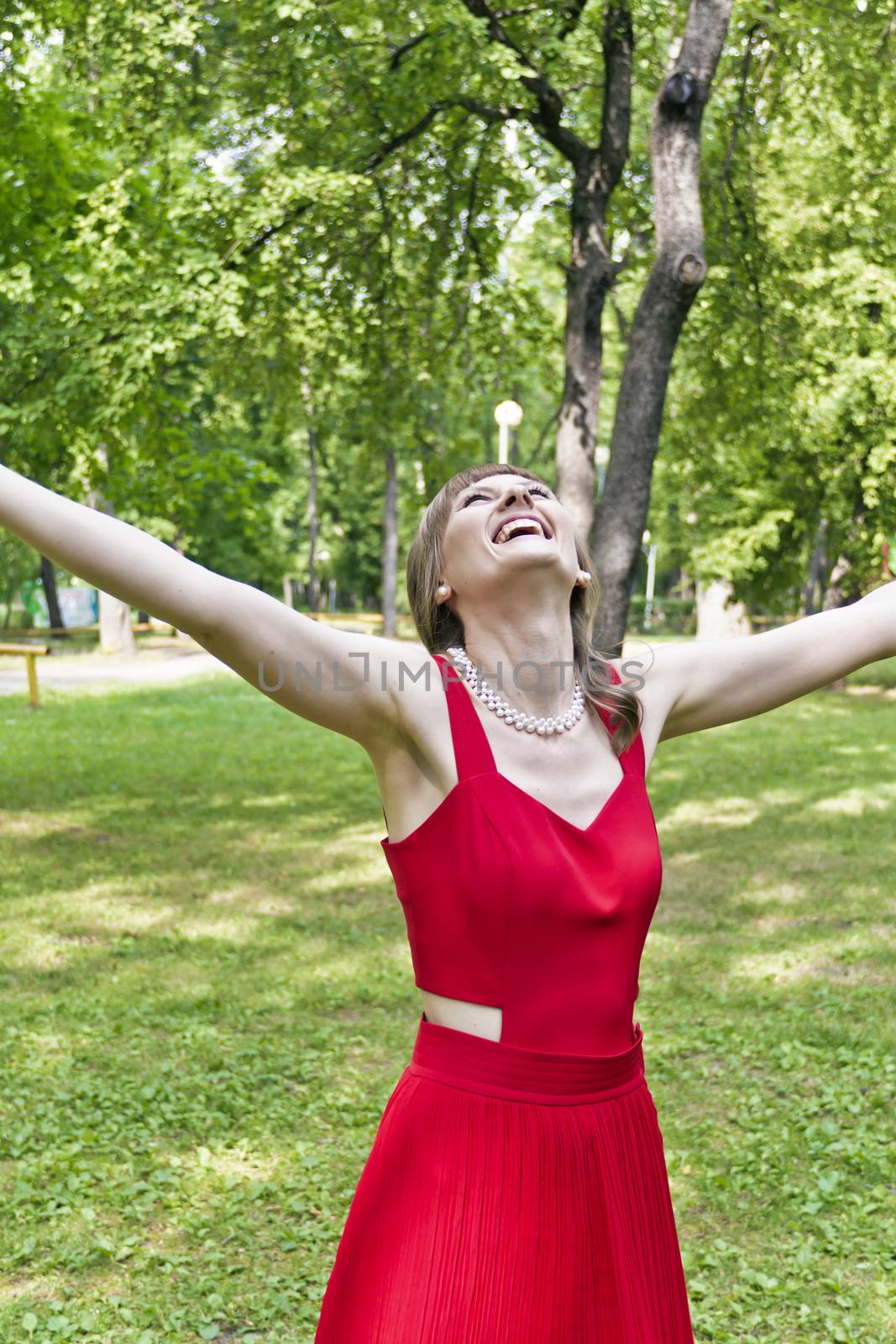 Beautiful lady in red are standing at summer day with upward hands