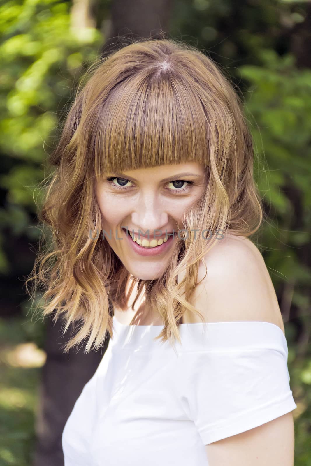 Vertical portrait of smiling woman with blond hair on summer background