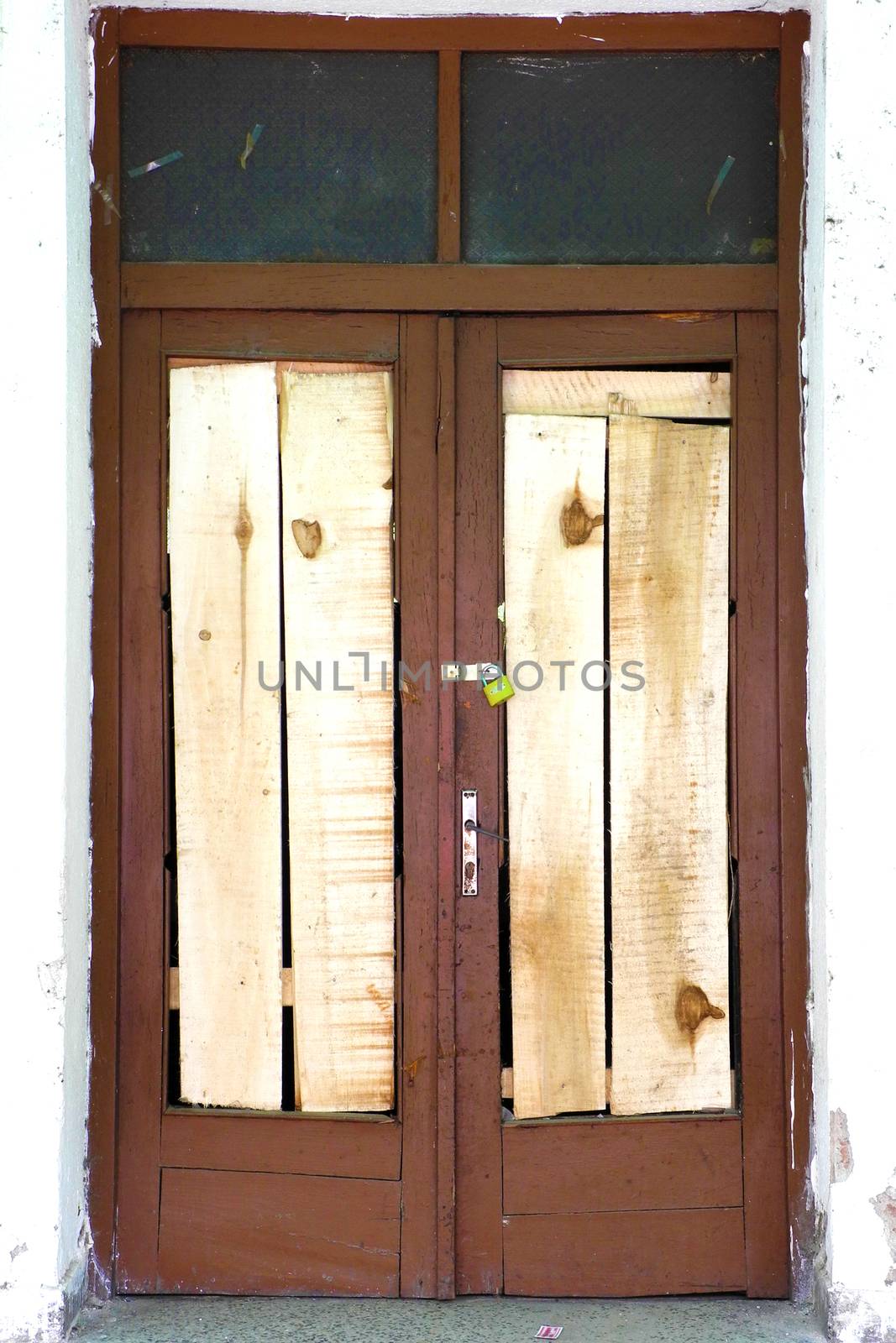 Old wooden brown rustic locked door with white wall