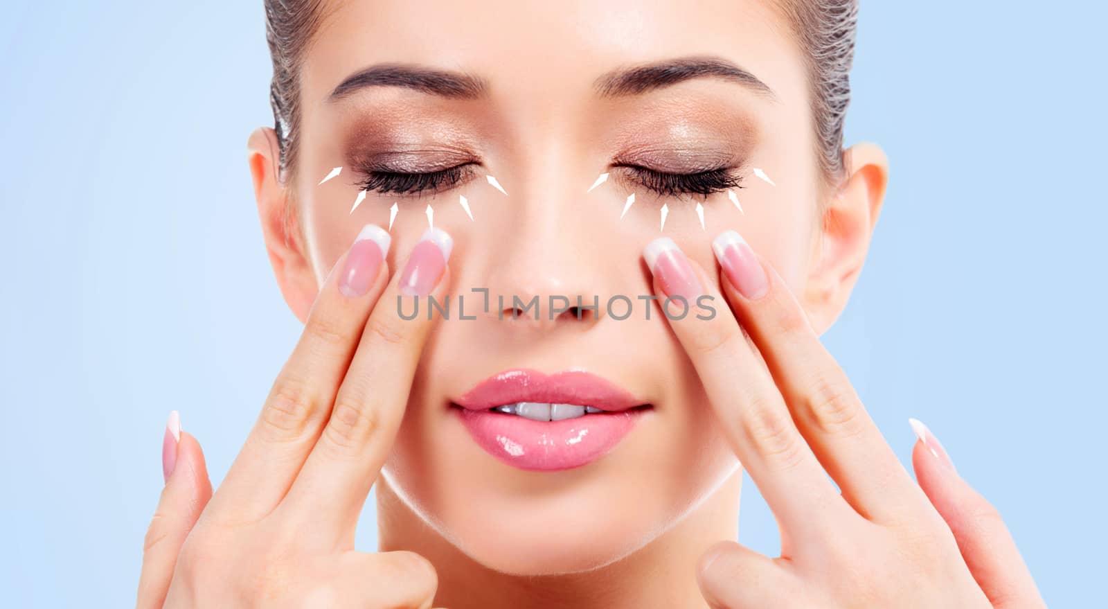 Closeup shot of young beauty woman massaging her face. Facial massage concept. Isolated on light blue background