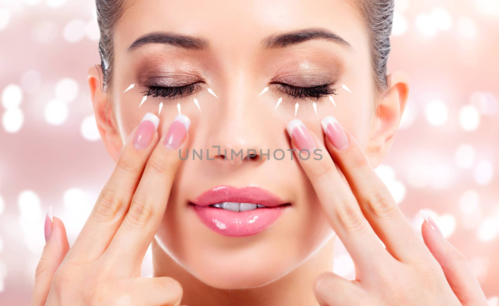 Pretty woman massaging her face, skin treatment concept. Abstract background with blurred lights