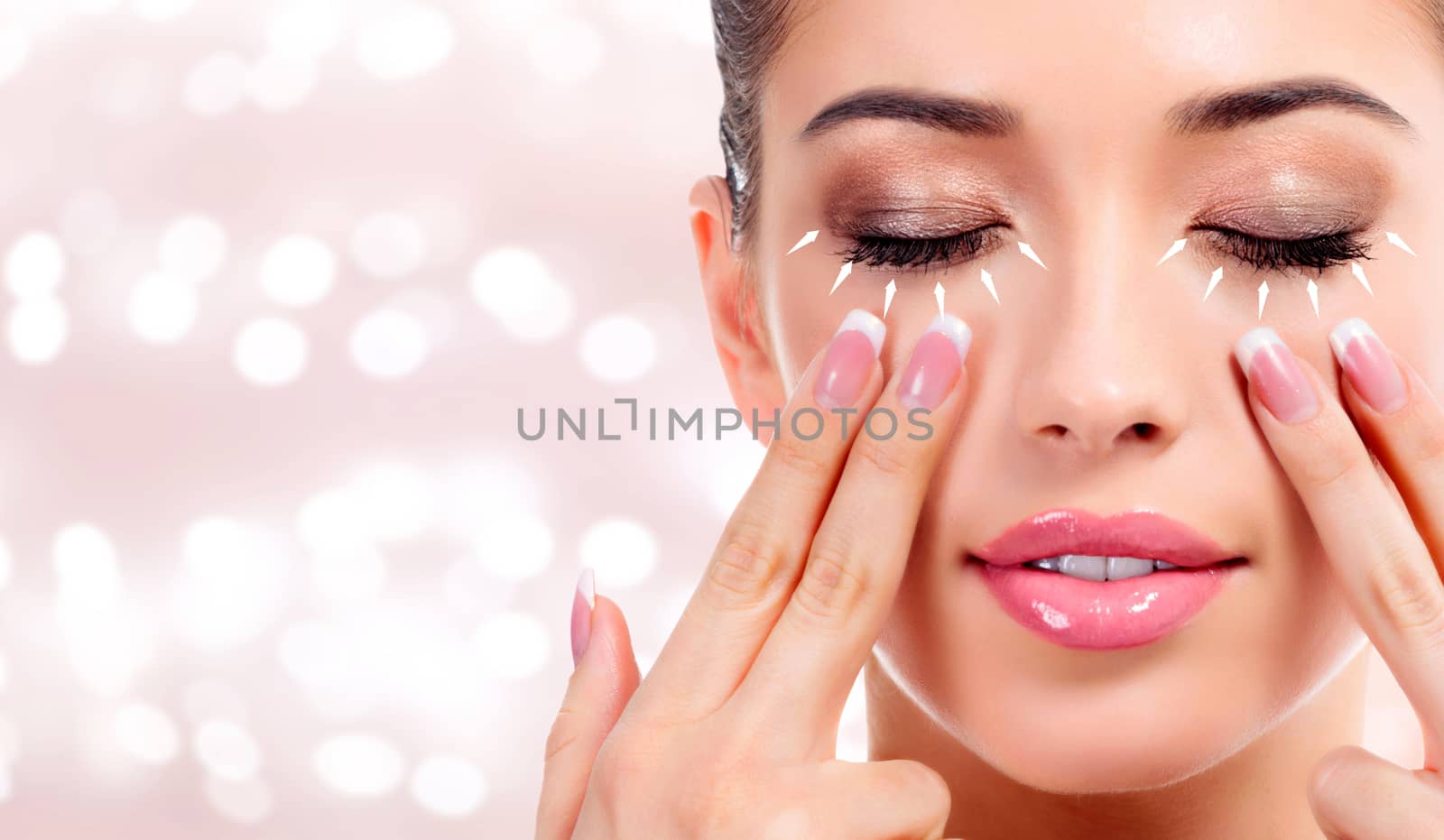 Pretty woman massaging her face, skin treatment antiaging concept. Abstract background with blurred lights