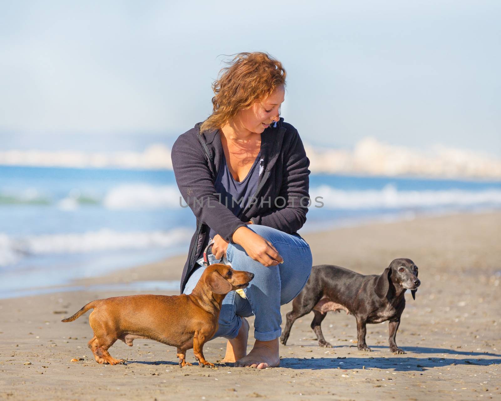 dogs and woman on the beach by cynoclub