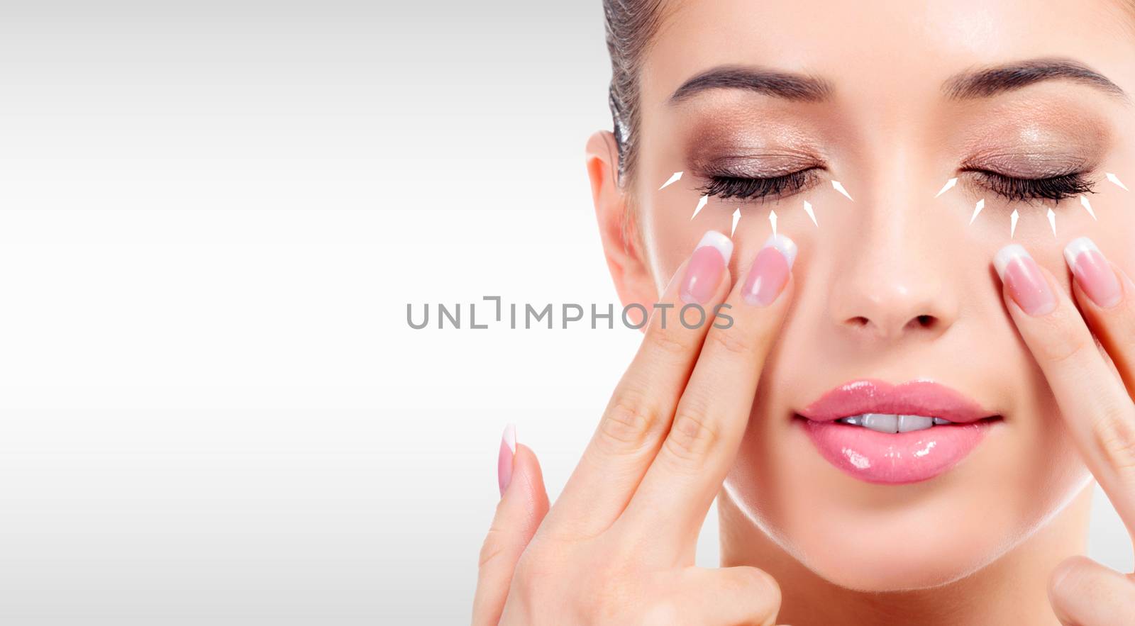Closeup shot of young beauty woman massaging her face. Facial massage concept. Pretty girl against a grey background with copyspace
