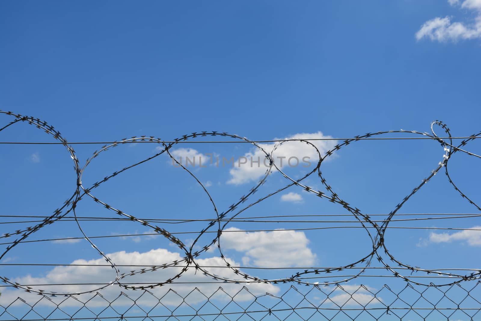 Detail of a fence with sharp edges against blue sky with clouds