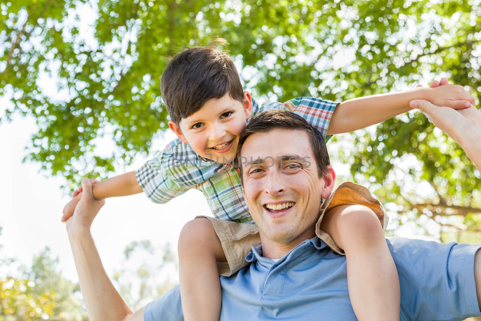 Mixed Race Father and Son Playing Piggyback Together in the Park by Feverpitched