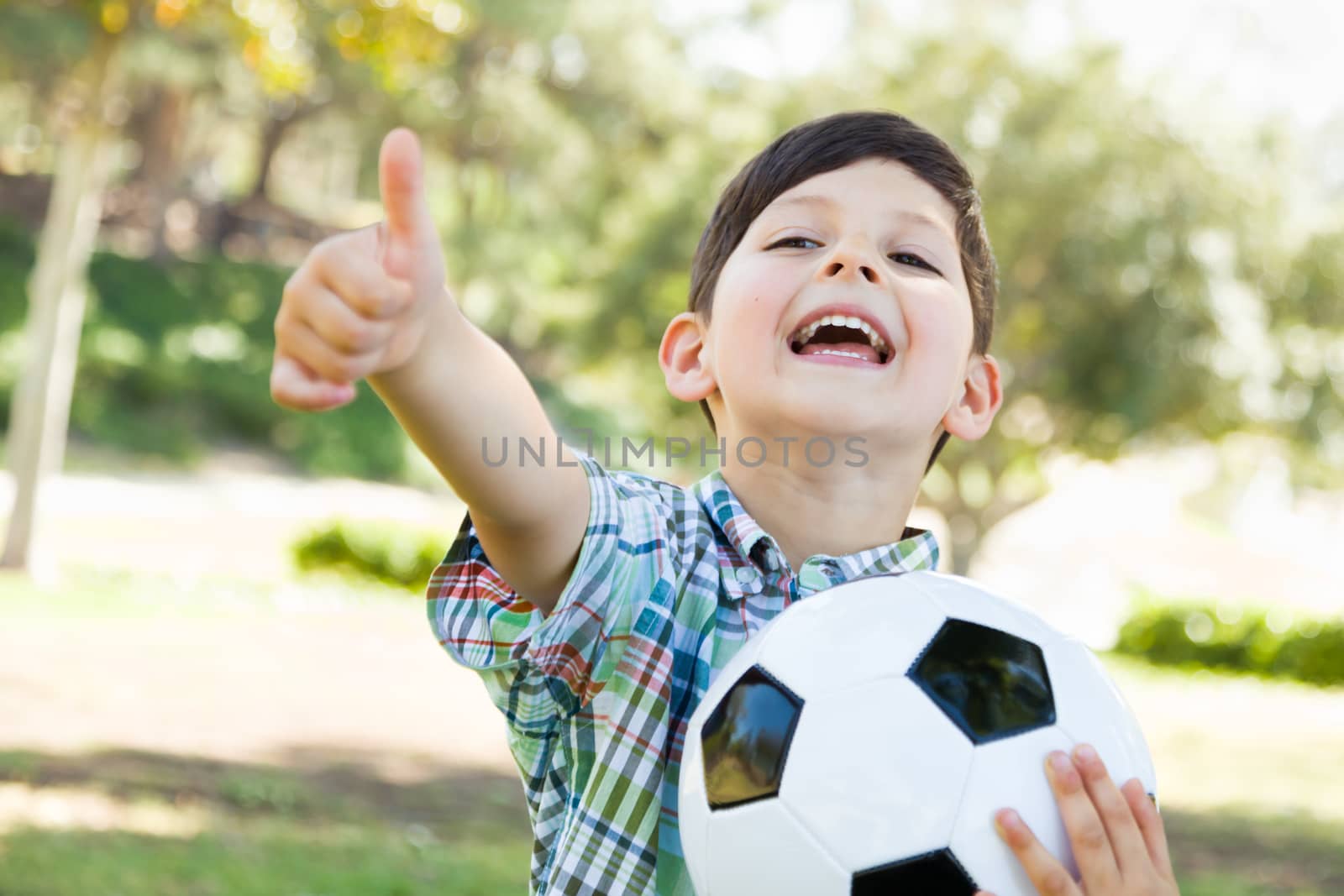 Cute Young Boy Playing with Soccer Ball and Thumbs Up Outdoors in the Park.