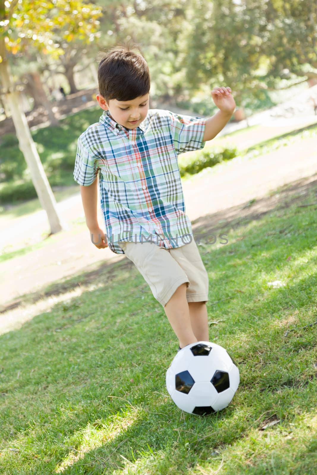 Cute Young Boy Playing with Soccer Ball Outdoors in the Park.